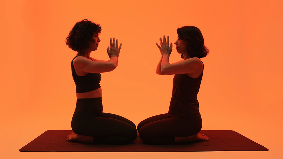 Two practitioners kneeling face to face, palms almost touching
