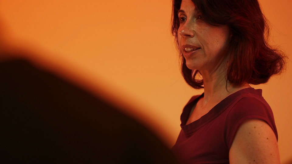 Blandina in conversation, in profile against a warm wall