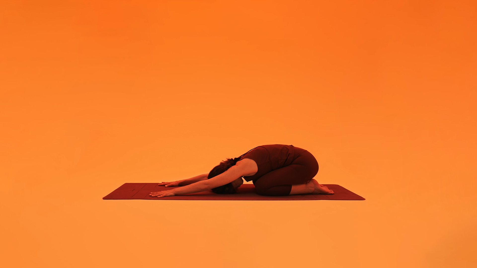 Child's pose on a mat, arms stretched forward and forehead resting down
