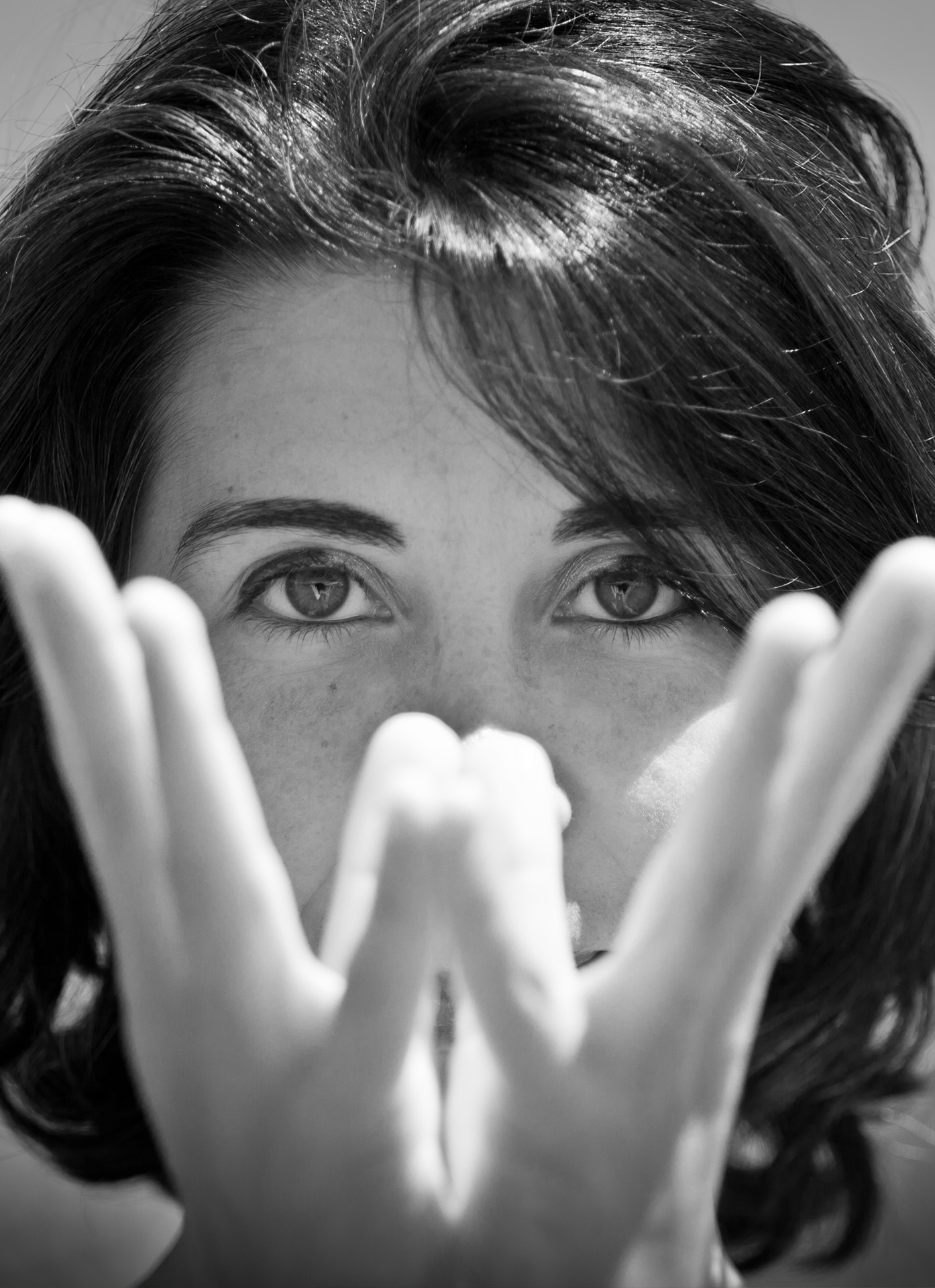 Portrait in black and white, eyes above hands held in a mudra
