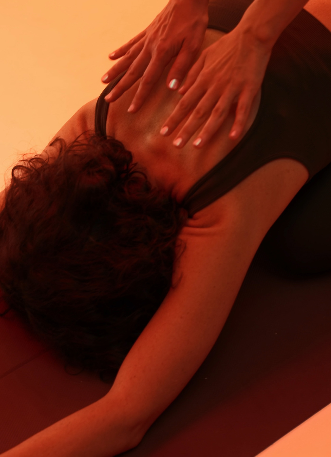 A teacher's hands resting on a student's back in child's pose
